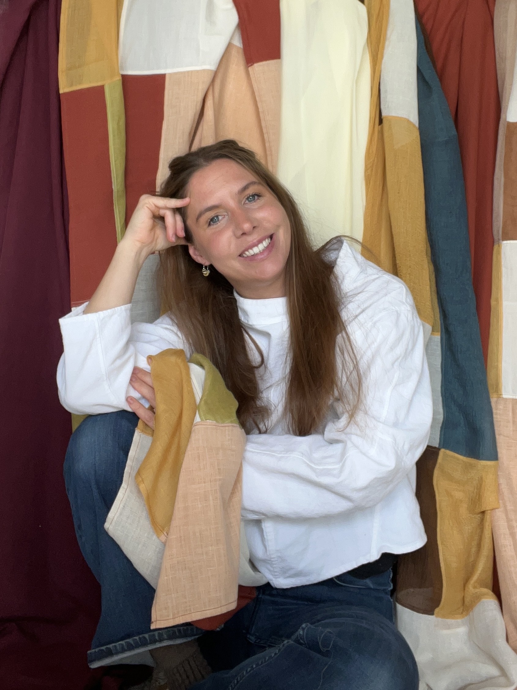 Carlota, créatrice de Bo·Jour, assise devant de grands rideaux patchwork